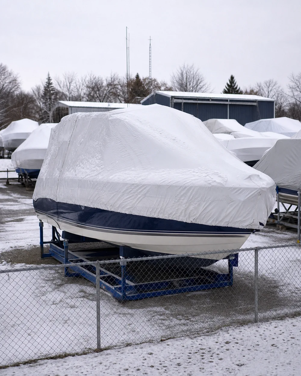 Fenced winter storage yard, snow on covered boats